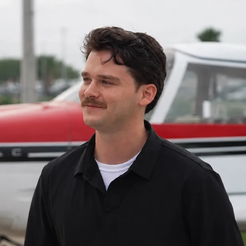 Dominick, a ferry pilot for Settle Ferry Group, standing in front of a red and white Piper Cherokee